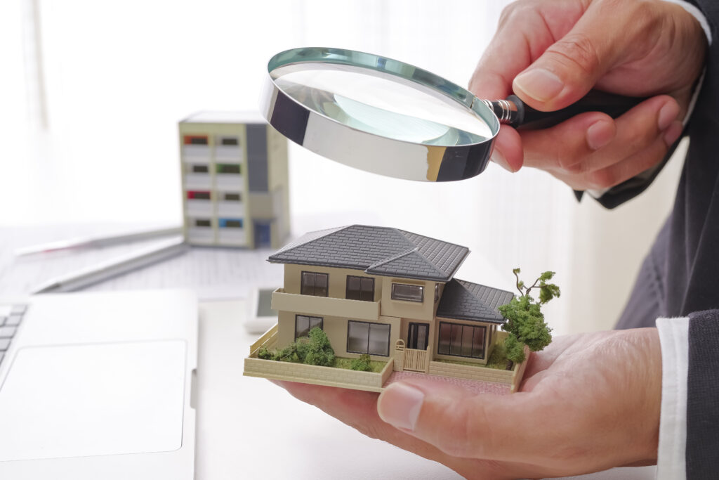 住宅の模型と虫眼鏡を持つ手
